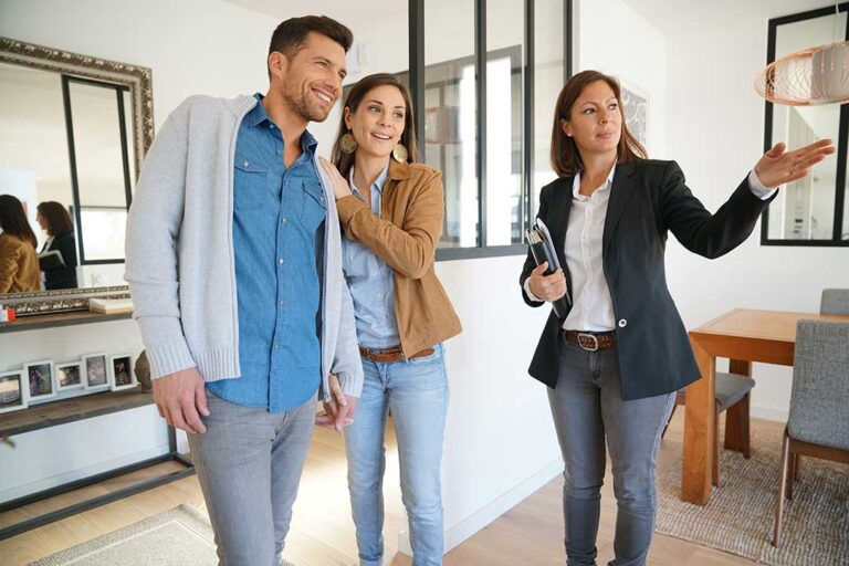 Two people reviewing home documents at a kitchen table with a set of house keys nearby.